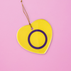 Ceramic heart shaped Intersex ornament with the intersex pride colors on a pink background. Heart Intersex pride ornament