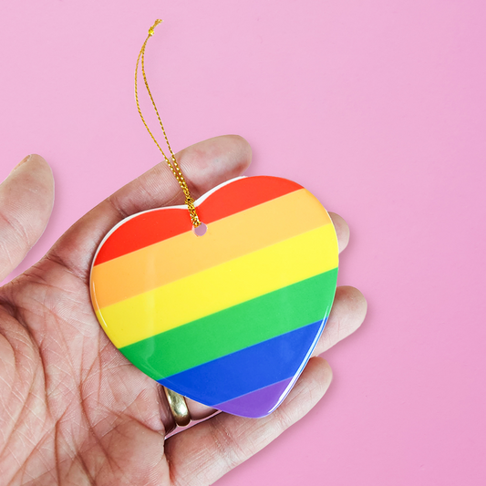 Ceramic heart shaped LGBTQ ornament with the gay pride colors on a pink background. Heart-shaped gay pride ornament
